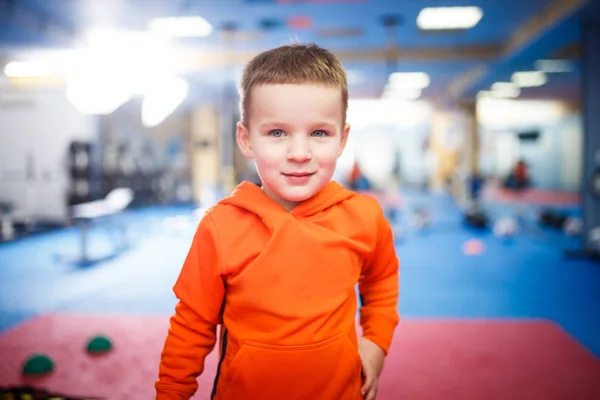 Porträt eines Kindes, das in der Turnhalle posiert. Thema ist die körperliche Entwicklung von Kindern. Ein Sportlerjunge in Sportkleidung blickt in die Kamera. Kindheit und Gesundheit — Stockfoto