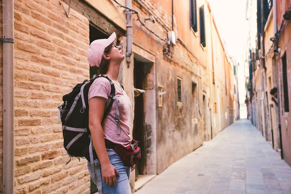 La muchacha turística en caucásico se para en la calle vieja desierta en Venecia en italia y mira hacia arriba en verano — Foto de Stock