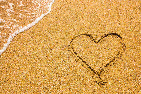 символ сердца на песке. Концепция летнего отдыха. Романтическое любовное прошлое. Тема Валентина Дэя. Вид сверху. Сердце, нарисованное в морском песке, мягкая волна в солнечный день
