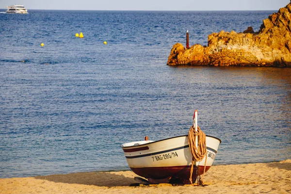 Traditionele oude houten vissersboot op het rotsachtige strand. Reisconcept. Costa Brava, Spanje. Vissersboot rusten op gouden zandstrand met uitzicht op de blauwe zee. Houten Vissersboot Spanje — Stockfoto