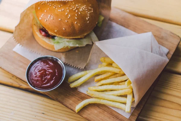 Fresh tasty burger and french fries on wooden table. french fries and bbq sauce on wood plate. street food burger and fried potatoes. Unhealthy food. fast food and unhealthy eating concept