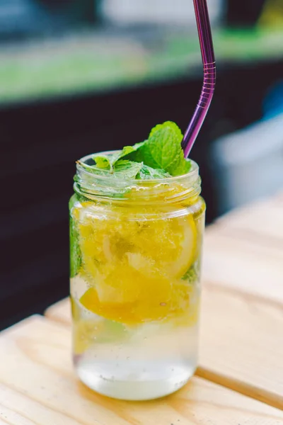 lemonade cocktail garnished with lemon and mint On Table. non alcoholic drink in vintage mason jar glass. lemon drink in glass with metal straw, natural eco friendly reusable, zero waste lifestyle