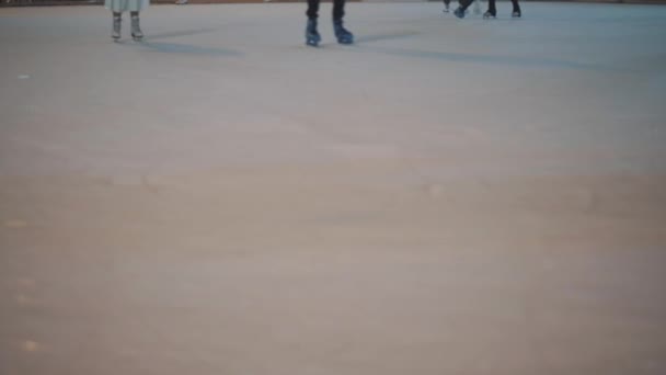 Piernas de personas irreconocibles cabalgan en una pista de hielo abierta de la ciudad por la noche. Patinaje de invierno pista pública en la Feria de Navidad. La gente patina en la pista en Kiev, Ucrania en la zona de contratos — Vídeos de Stock