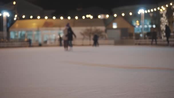 Le gambe di persone irriconoscibili cavalcano su una pista di pattinaggio su ghiaccio aperta in città la sera. Pattinaggio invernale pista di pattinaggio pubblico sulla Fiera di Natale. Persone pattinare sulla pista di pattinaggio a Kiev, Ucraina sulla zona del contratto — Video Stock