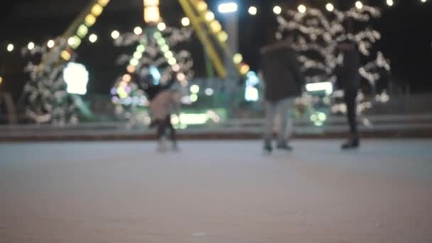 Pernas de pessoas irreconhecíveis montam em uma pista de gelo aberta da cidade à noite. Patinação de inverno pista pública na Feira de Natal. As pessoas patinam na pista em Kiev, Ucrânia, na área contratual — Vídeo de Stock