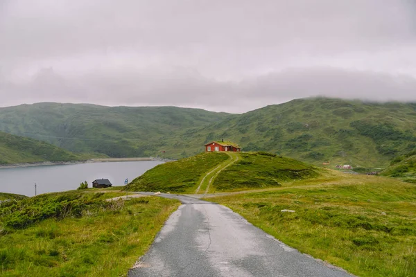 Casa de verano de madera noruega con vistas al lago escénico, Noruega, Escandinavia. Casa de campo junto al lago en Rural. Cabaña cubierta de turba en el lago. Típica cabaña cubierta de hierba en Noruega. Cabaña de pesca típica de rorbu rojo — Foto de Stock