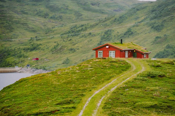 Casa de verano de madera noruega con vistas al lago escénico, Noruega, Escandinavia. Casa de campo junto al lago en Rural. Cabaña cubierta de turba en el lago. Típica cabaña cubierta de hierba en Noruega. Cabaña de pesca típica de rorbu rojo — Foto de Stock