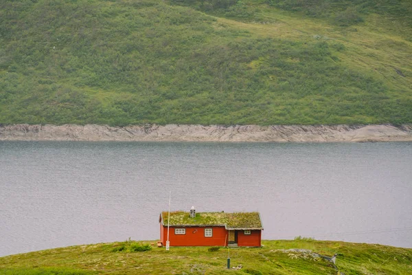 Casa norvegiană de vară din lemn cu vedere la lacul pitoresc, Norvegia, Scandinavia. Cabană lângă lac în mediul rural. Cabană acoperită cu turbă pe lac. O colibă tipică de iarbă acoperită în Norvegia. Coliba tipică de pescuit rorbu roșu — Fotografie, imagine de stoc