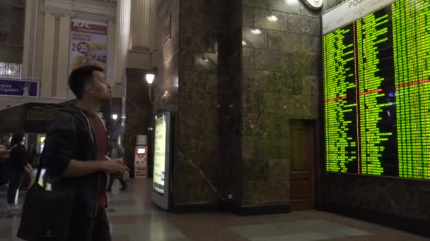 Kiev, Ukraina - 8 mars 2018: Tågschema. Centralstationen i Kiev. Passagerare som tittar på de elektroniska avgångar och ankomster ombord på centralstationen i Kiev — Stockvideo