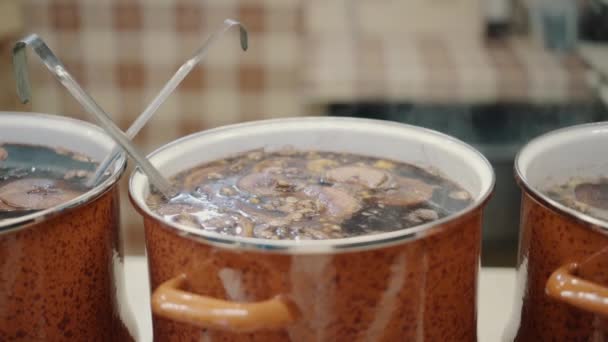 Enorme pannen met warme glühwein op kerstfeest. straatwinkel met traditionele glühwein. Close-up warme wijnpan 's avonds op de kerstmarkt. Straat eten, glühwein gekookt in bad in brand — Stockvideo