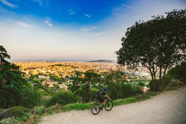 Açık hava aktivitelerinin teması, doğadaki spor yaşam tarzı. Gün batımında Barcelona manzaralı dağ Tibidabo 'sunda bisiklet süren bir adam.