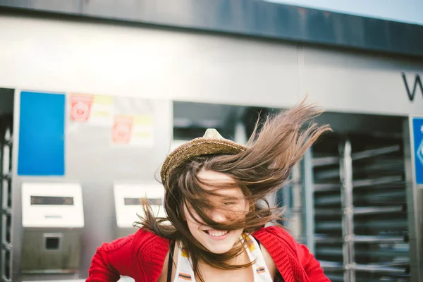 Hermosa joven sonriendo, es feliz, feliz en un sombrero, una camisa roja sobre la ciudad — Foto de Stock