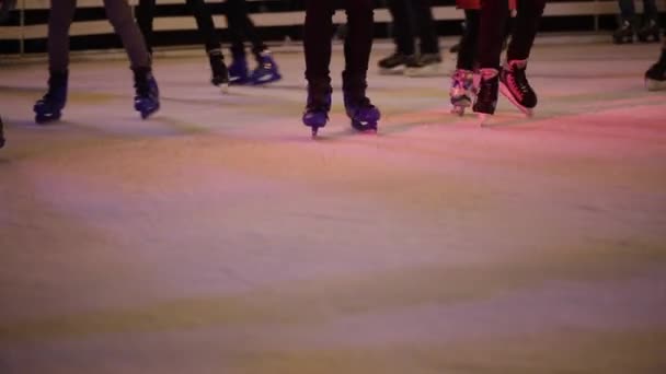 Le soir, des jambes de gens méconnaissables roulent sur une patinoire ouverte de la ville. Patinoire d'hiver sur la foire de Noël. Les gens patinent sur la patinoire à Kiev, Ukraine sur la zone contractuelle — Video