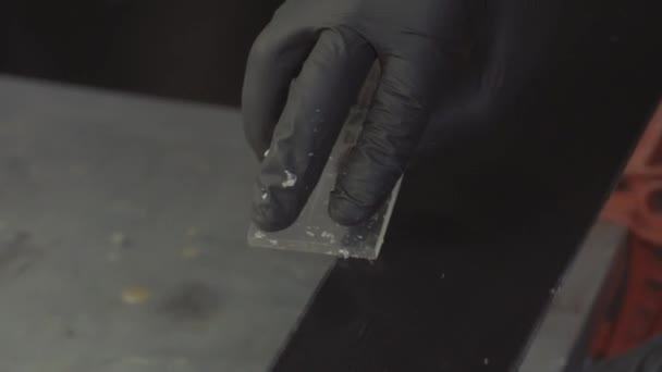 Entretien du ski. Enlever l'excès de cire du grattoir en plastique de la base de ski de course. Service et réparation de ski. Ouvrier d'atelier d'hiver faisant réparation de base. Service d'atelier de location. Service de réparation en atelier de ski