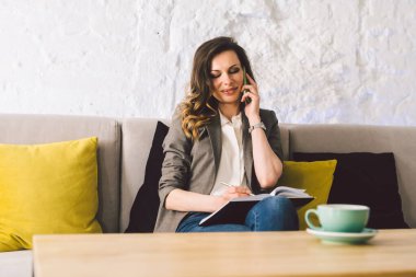 İş kadını kahve dükkanında dizüstü bilgisayarla çalışıyor. Kadın cep telefonuyla arıyor, boş zamanlarında kafede tek başına oturuyor. Serbest yazar blogcusu. Ofisin dışında çalış. Eş çalışma