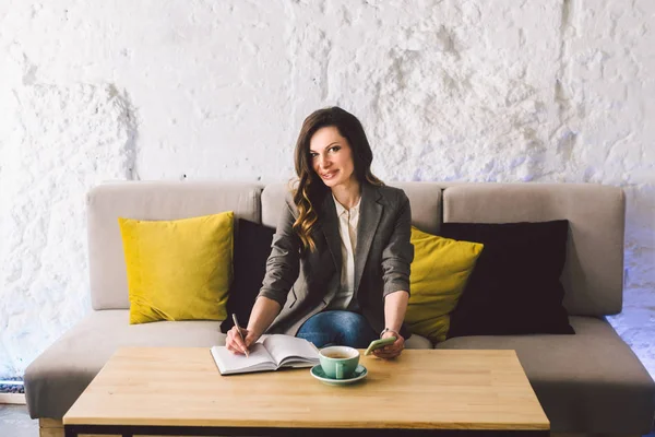 Escrever laticínios no caderno no café, conceito como memória da vida. mulher com telefone celular e caneta na mesa de madeira com xícara de café no café. Sorrindo Empresária Fazendo Notas Bloco de Notas — Fotografia de Stock