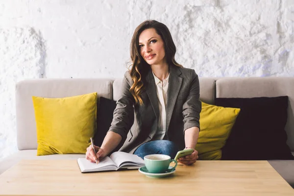 Escrever laticínios no caderno no café, conceito como memória da vida. mulher com telefone celular e caneta na mesa de madeira com xícara de café no café. Sorrindo Empresária Fazendo Notas Bloco de Notas — Fotografia de Stock