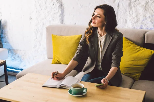 Escrever laticínios no caderno no café, conceito como memória da vida. mulher com telefone celular e caneta na mesa de madeira com xícara de café no café. Sorrindo Empresária Fazendo Notas Bloco de Notas — Fotografia de Stock