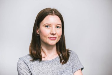 beyaz stüdyo arka plan üzerinde gri t-shirt gülümseyen şık genç güzel Kafkas kadın portresi, izole, doğal bir görünüm, uzun kahverengi saçlı