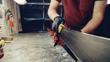 Kayak servisi atölyesinde çalışan erkek kayakları bileyip onarıyor. Kayak kenarlarını, elmas taşla tutturulmuş kenar ayarlama aleti ile keskinleştiriyorum. Kayak kaldırımının tema onarımı