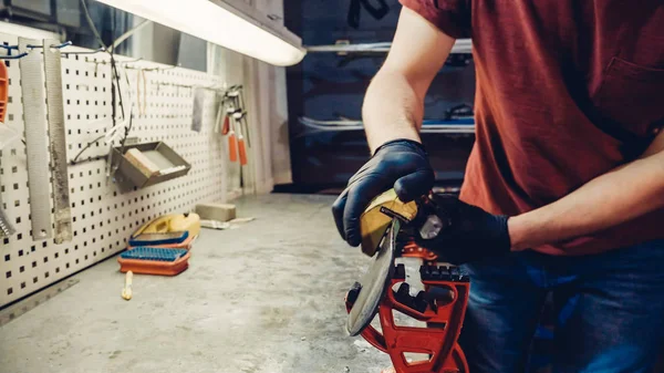 Male worker of ski service workshop doing sharpening and repair of skis. Sharpening ski edges with a manual side-edge tuning tool fitted with a diamond stone. Theme repair of ski curb