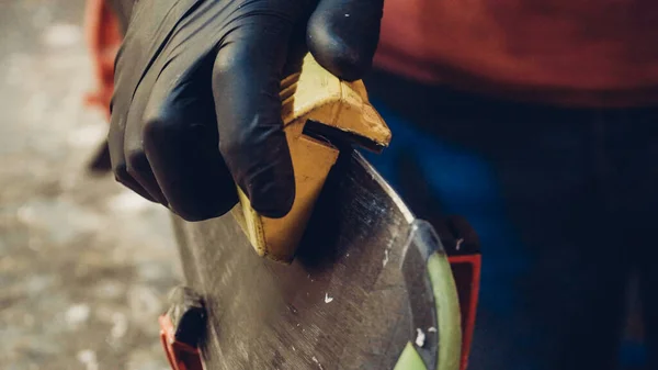 Male worker of ski service workshop doing sharpening and repair of skis. Sharpening ski edges with a manual side-edge tuning tool fitted with a diamond stone. Theme repair of ski curb