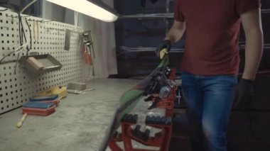 Kayak servisi atölyesinde çalışan erkek kayakları bileyip onarıyor. Kayak kenarlarını, elmas taşla tutturulmuş kenar ayarlama aleti ile keskinleştiriyorum. Kayak kaldırımının tema onarımı