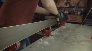 Kayak servisi atölyesinde çalışan erkek kayakları bileyip onarıyor. Kayak kenarlarını, elmas taşla tutturulmuş kenar ayarlama aleti ile keskinleştiriyorum. Kayak kaldırımının tema onarımı
