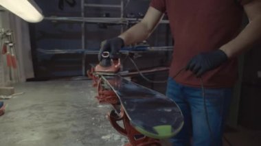 Kayak tabanına demirle sıcak mum sürüyorum. Kayak tabanına kayak cilası sürüyorum. Kayak zemini ayarlaması. Kayak demiri ve balmumu çubukları. Kayak servisi ve onarım. Atölye kayak servisinde tamirci. Atölyede Kayak Yapan Adam