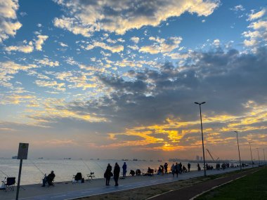 İstanbul 'da Marmara Denizi kıyılarında gün batımında balık tutan balıkçılar