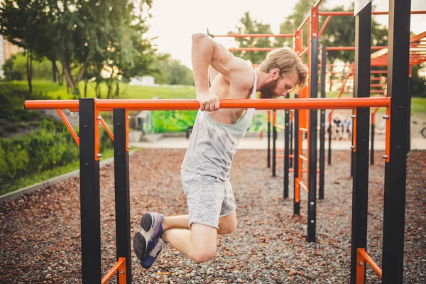 Fit Man Harjoitus Käsivarret Upotukset Vaaka Baarit Koulutus Triceps Ja Biceps Doing Push Ups. Komea mies treenaa rinnakkaisissa baareissa. Mies urheilija harjoitukset rinnakkain baareja ulkona — kuvapankkivalokuva