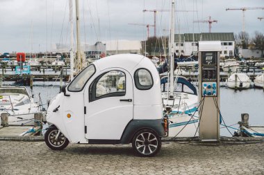 Danimarka 'nın Kopenhag şehrinde deniz kenarında küçük bir elektro araba şarj oluyor. Elektrikli araba şarj oluyor. Araba için alternatif çevre enerjisi. Çevresel koruma. Küresel ısınma