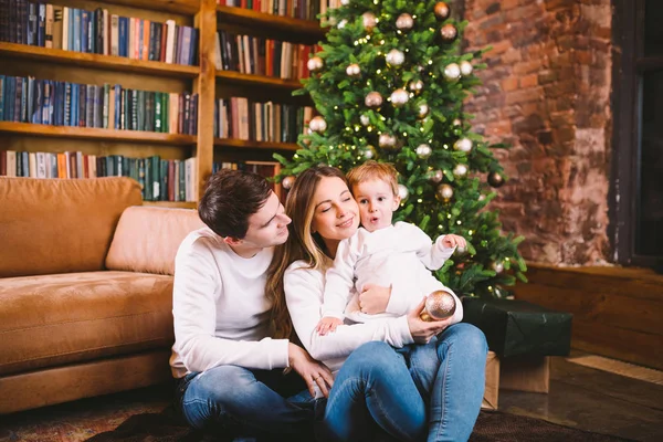 Family Christmas Concept. Lovely family sits near Christmas tree on winter evening. Happy family with son on floor near sofa At home. Family At Home At New Year Time. family enjoy new year holidays — Stock Photo, Image