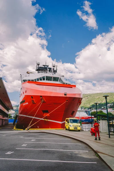 Dos paramédicos noruegos con uniformes rojos están descansando cerca de una ambulancia estacionada en un puerto cerca de un gran barco. Tema Salud y medicina en Noruega, Bergen julio 28, 2019 —  Fotos de Stock