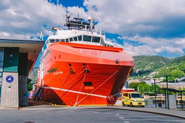 Dos paramédicos noruegos con uniformes rojos están descansando cerca de una ambulancia estacionada en un puerto cerca de un gran barco. Tema Salud y medicina en Noruega, Bergen julio 28, 2019 —  Fotos de Stock