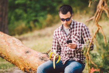 Açık havada muz yiyorum. Yürüyüş patikası. Tema yürüyüşü ve doğa seyahati. Turistler dinlenir ve babana yer. Ormanda piknik. Turistler abur cubur yerler. Vitamin yüklemesi