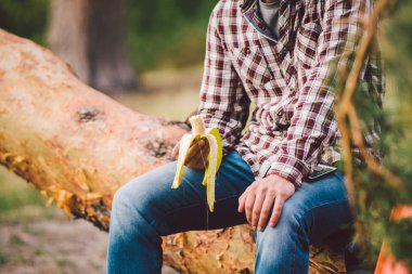Açık havada muz yiyorum. Yürüyüş patikası. Tema yürüyüşü ve doğa seyahati. Turistler dinlenir ve babana yer. Ormanda piknik. Turistler abur cubur yerler. Vitamin yüklemesi