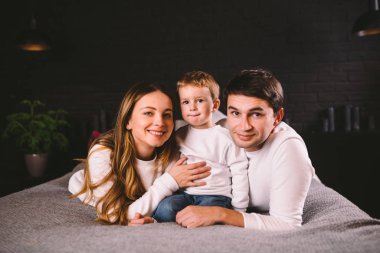 Anne-babalar, erkek bebekleriyle evde yatıyorlar. Geceleri evde çocuklu aileler yatar. Mutlu aile yatakta eğleniyor. Anne, baba ve çocuk akşamları yatak odasında oynuyorlar. Çatı katı biçimi