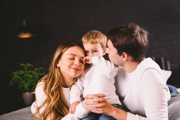 Gelukkig gezin met plezier liggend op bed thuis. Gelukkige familie in bed. Mam, pap en zoon liggen op de slaapkamer binnen de deur. vader, moeder en kind ontspannen bedstede in loft stijl appartement in de avond — Stockfoto