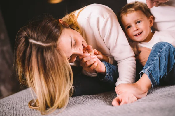 Família feliz está se divertindo no quarto. Estou a gostar de estar juntos. Os pais fazem cócegas ao filho enquanto estão deitados na cama. Família alegre brincando juntos na cama. Sorrindo família se divertindo — Fotografia de Stock