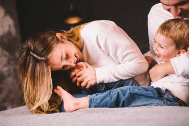 Mutlu bir aile evde yatıp eğleniyor. Yatakta mutlu bir aile. Anne, baba ve oğul yatak odasında uzanıyorlar. Baba, anne ve çocuk akşamları çatı katında dinleniyor.