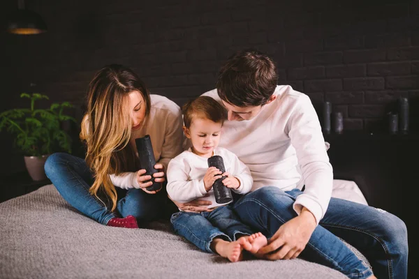 Glad familj har roligt i sovrummet. Njuter av att vara tillsammans. Föräldrarna kittlar sin son när de ligger i sängen. Glada familj leker tillsammans på sängen. Leende familj som har roligt — Stockfoto