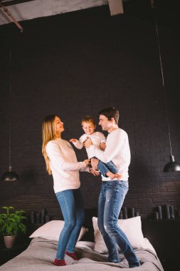 Aile yatakta birlikte zıplıyor. Aile eğlencesi. Yatakta zıplayan güzel aile. Beyaz anne baba ve oğul aktif bir akşam tatili, hafta sonları eğlence ve neşe.