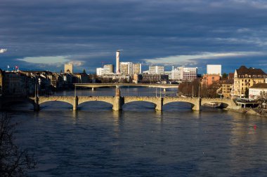 Basel şehri ve Rhine nehrinin manzarası. Miras, güzel. Kışın güneşli havalarda İsviçre şehri Basel. Ren seti manzarası ve insanların yürüyüp rahatladığı nehir manzarası.