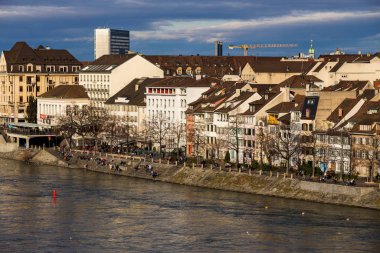 Basel şehri ve Rhine nehrinin manzarası. Miras, güzel. Kışın güneşli havalarda İsviçre şehri Basel. Ren seti manzarası ve insanların yürüyüp rahatladığı nehir manzarası.