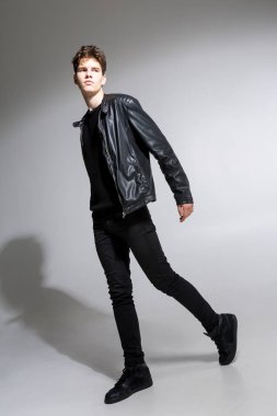 Beyaz arka planda koyu renk elbiseli genç adam portresi. Genç Erkek Moda Moda Model Pozisyonu. Siyah ceketli çekici genç manken.