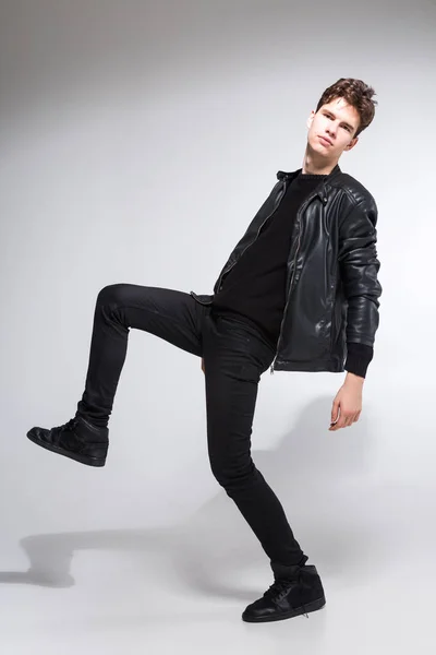 Full length portrait of young fit man in dark cloths on the white background. Young Male Fashion Model Posing In Casual Outfit. Attractive young fashion model wearing black in leather jacket — Stock Photo, Image