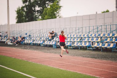 Stadyumda Koşan Kadın. Stadyum pistinde koşan genç bir kadın. Gol başarı konsepti. Spor sahasında spor koşusu. Sağlık teması. Kilo verme başarısı için spor antrenmanı kardiyosu