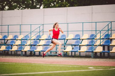 Stadyum pistinde koşan bayan koşucu, koşan ve dışarıda koşan kadın sporcu, spor ve fitness konsepti. Spor giyimli genç bir kadın stadyumda antrenman yapıyor. Spor yaşam tarzı konusu