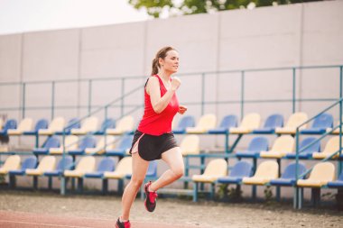 Stadyumda Koşan Kadın. Stadyum pistinde koşan genç bir kadın. Gol başarı konsepti. Spor sahasında spor koşusu. Sağlık teması. Kilo verme başarısı için spor antrenmanı kardiyosu